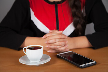Woman holding mobile phone, he drinking coffee.