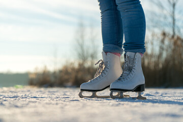 Close-up of legs in ice-skates while standing on a frozen lake in winter