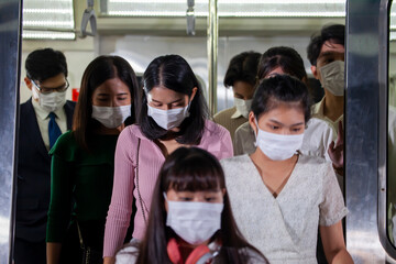 Group of Asian passenger getting off metro subway train at night for transportation with everyone wearing facial mask for pollution and protection from coronavirus in new normal and social distancing