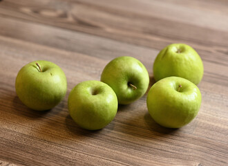 Green apples on a wooden table. Image with selective focus.