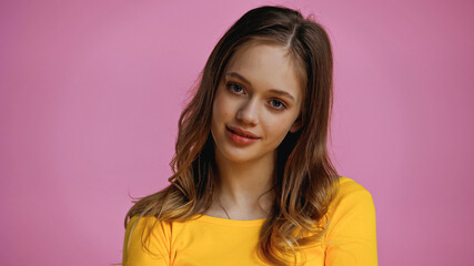 Fototapeta premium smiling teenage girl looking at camera isolated on pink
