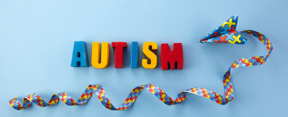Autism awareness. paper plane in origami style with autism awareness ribbon ant worl autism on blue...