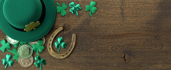 St Patricks Day border of shamrocks, gold coins and leprechaun hat on rustic wooden background