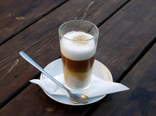 Caffe latte Macchiato, a glass of coffee with frothed milk on a wooden background. Its coffee time.