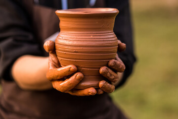 Pottery man hands hold clay pot on his workshop