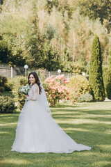 Beautiful bride with wedding flowers bouquet, attractive woman in wedding dress. Happy newlywed woman. Bride with wedding makeup and hairstyle. Smiling bride. Wedding day. Gorgeous bride. Marriage.