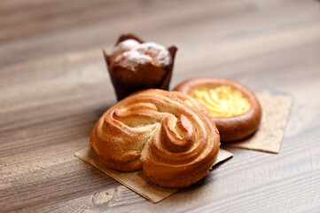 Sweet rolls and cupcake on a wooden table. Image with selective focus.