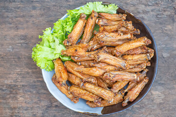 Fried chicken wings with fish sauce with salad vegetables on a white plate placed on a wooden table. Close-up photo. Space for text. Concept of foods