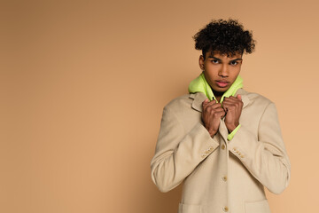 young african american man adjusting blazer on beige