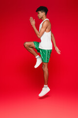 full length of sportive african american man in green shorts working out on red