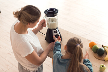 Mom and daughter make fresh smoothie in blender, healthy food lifestyle, top view, high angle