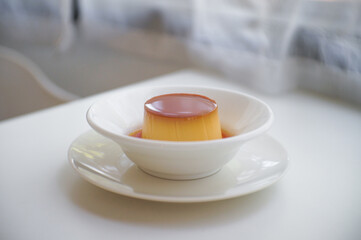 Pudding caramel custard in White ceramic bowl on table.
