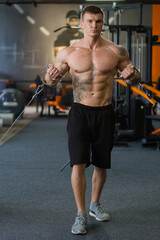 Naklejka premium an athlete in the gym performs an exercise for the hands on the simulator. sports lifestyle. beauty and health.