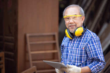 Male carpenter in a construction workshop, using a digital tablet