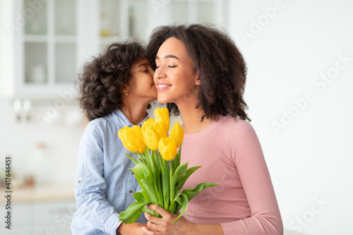 Black girl celebrating mother's day, greeting mum with flowers