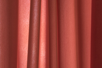 Bright red curtain decoration with vertical pleats. Smooth folds of fabric.
