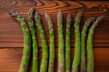Thick, fully grown green asparagus tips, charred and brushed boards in the background. 