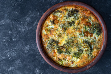 Frittata with egg, pepper, onion, broccoli and cheese on wooden table. Italian egg omelette
