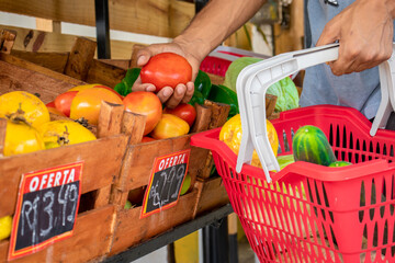Homem segurando cesta de frutas e legumes no mercado.