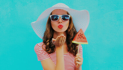 Portrait of young woman blowing her red lips with slice of watermelon on a blue background