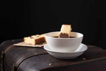 Chocolate caliente en taza blanca con bizcocho en una vieja maleta marrón. Desayuno Español	