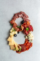 Italian appetizers or antipasto set with gourmet food on stone table. Mixed cheese and meat snacks of the number eight. International Women's Day. top view