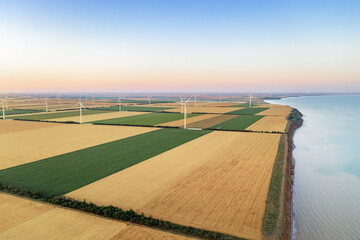 Windmills on the seaside. Wind turbine power generators at sunset. Alternative energy production