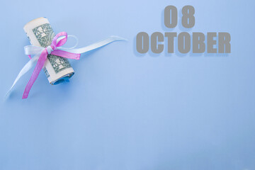 calendar date on blue background with rolled up dollar bills pinned by blue and pink ribbon with copy space. October 8 is the eighth day of the month