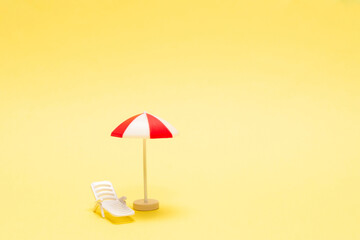 Two sun loungers and a red umbrella on a yellow background.