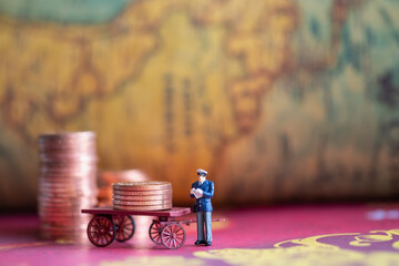 Miniature : inspector stood next to the coin and the cart. Vintage business concept background.