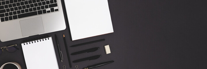 Banner with laptop and office supply on a black background. Online business organized workspace, distance work concept with open notepad mockup.