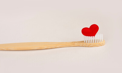 Bamboo toothbrush with white bristles and a red heart on a white background. Tooth disease concept, bleeding gums, blood when brushing teeth. Oral cavity care. copy space for text. Banner