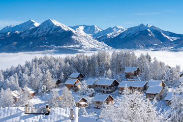 Fresh snow covers roofs and trees of Laye winter ski resort in Champsaur, French Alps. Hautes-Alpes, France