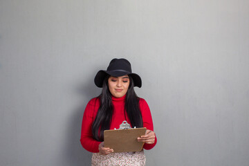 Hispanic woman looking at sales report on clipboard. businesswoman