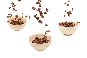 Chocolate corn flakes falling to the white bowl isolated on white. Motion.