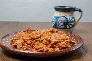 Mexican breakfast of egg and sausage in sauce with coffee. Mexican food