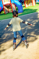 teenage girl in safety helmet-helmet and rollerblades rides along the track, exercising on a sunny...