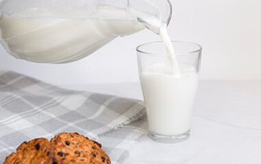 Fresh milk, oatmeal cookies are poured from a jug into a glass on a white background. A healthy snack or breakfast at home. Christmas drinks. Selective focus. copy space for text