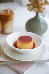 Homemade caramel custard pudding in a ceramic plate, deer on the book.