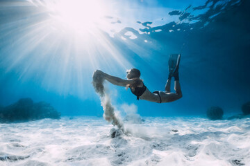 Free diver with fins and white sand in hands over sandy sea. Freediving in tropical ocean