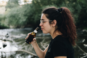 Chica joven bebiendo cerveza un día de verano en la naturaleza