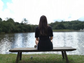 Moça refletindo e meditando em frente a lagoa em um dia fresco em uma fazenda em Atibaia, interior...