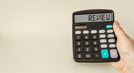 A female hand holds the calculator, the word REVIEW is written on the display.