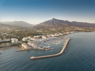 Aerial drone perspective of beautiful sunset over luxury Puerto Banus Bay in Marbella, Costa del Sol. Expensive lifestyle, luxury yachts. La concha mountain in background. Nueva Andalucía area