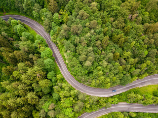 Winding road aerial view by drone. Brasov, Romania. There are huge snow mountains and long winding road in this area. This is a great place to drive and stop during a road trip.