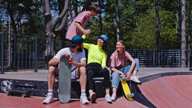 Very beautiful group of teen hipster friends in a modern skate park they socializing together while have a break they feeling very excited