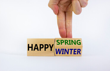 Symbol for the change from Winter to Spring. Businessman turns wooden cubes and changes words 'Happy Winter' to 'Happy Spring'. Beautiful white background, copy space. Happy Spring concept.
