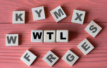 WTL - acronym on wooden cubes on a pink wooden background