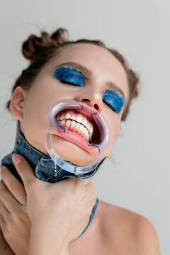 Portrait of a woman wearing a dental mouth retractor choking herself