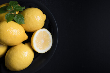Limones en un plato negro sobre fondo negro